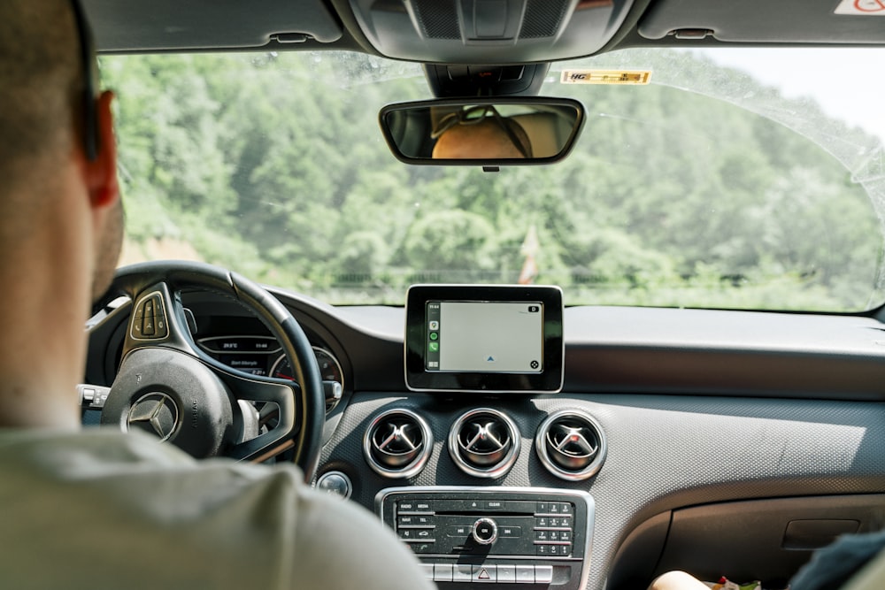 Un hombre conduciendo un coche con un dispositivo GPS en la mano