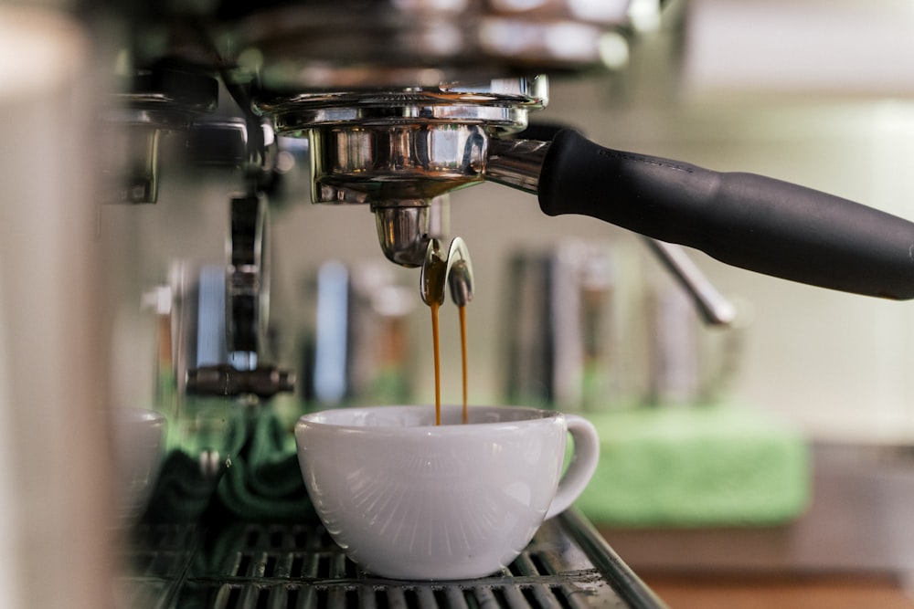 a cup of coffee being poured into a coffee machine