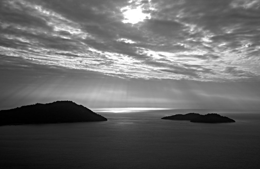 a black and white photo of the sun shining through the clouds