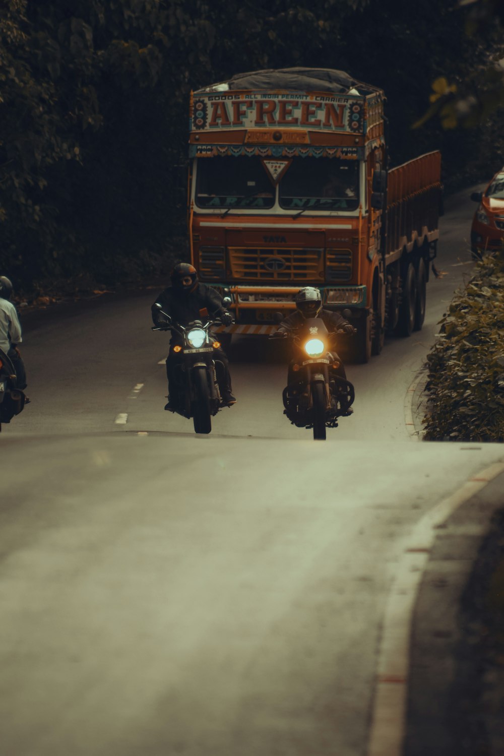 a couple of people riding motorcycles down a street
