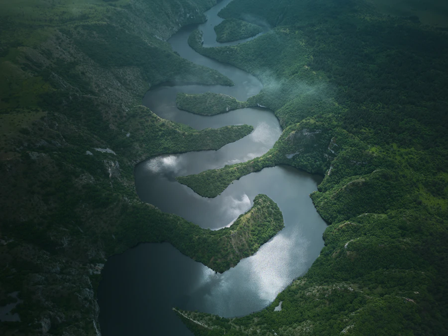 A river winding through forested hills in low mist, seen from the air.