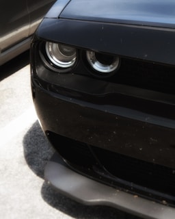 Close-up of a shiny black car's headlight reflecting the Parc Auto sign