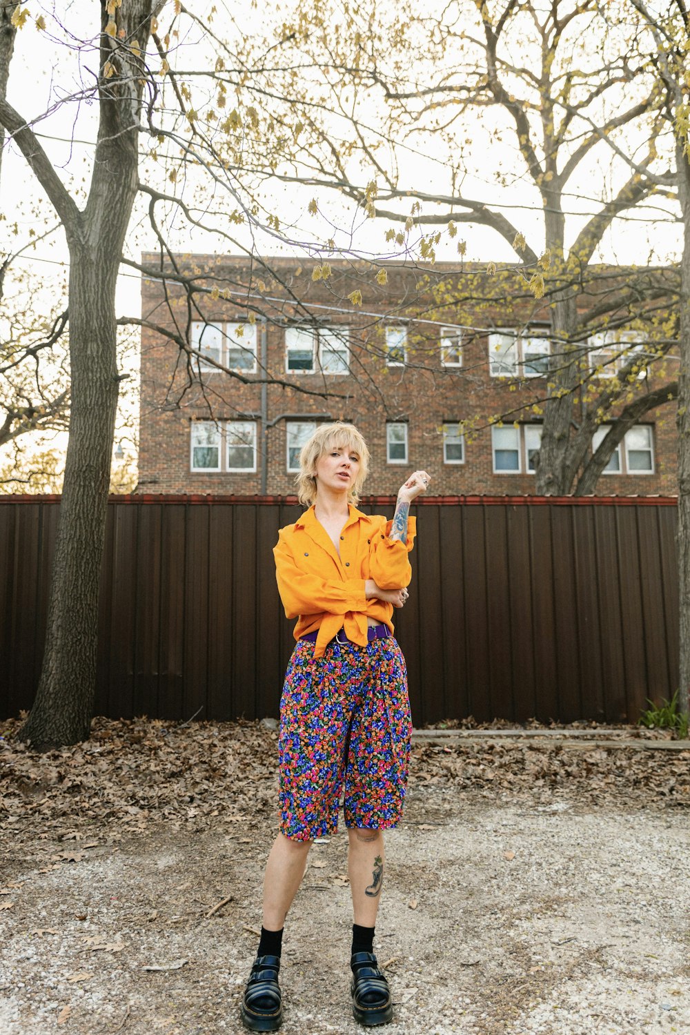 a woman standing in front of a brown fence