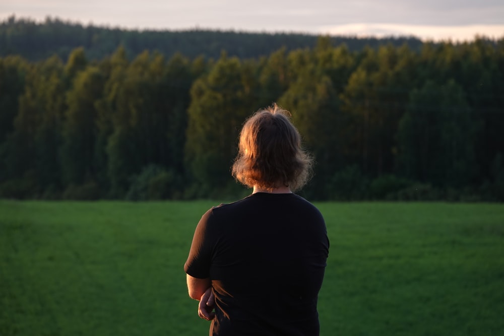 a woman standing in front of a lush green field