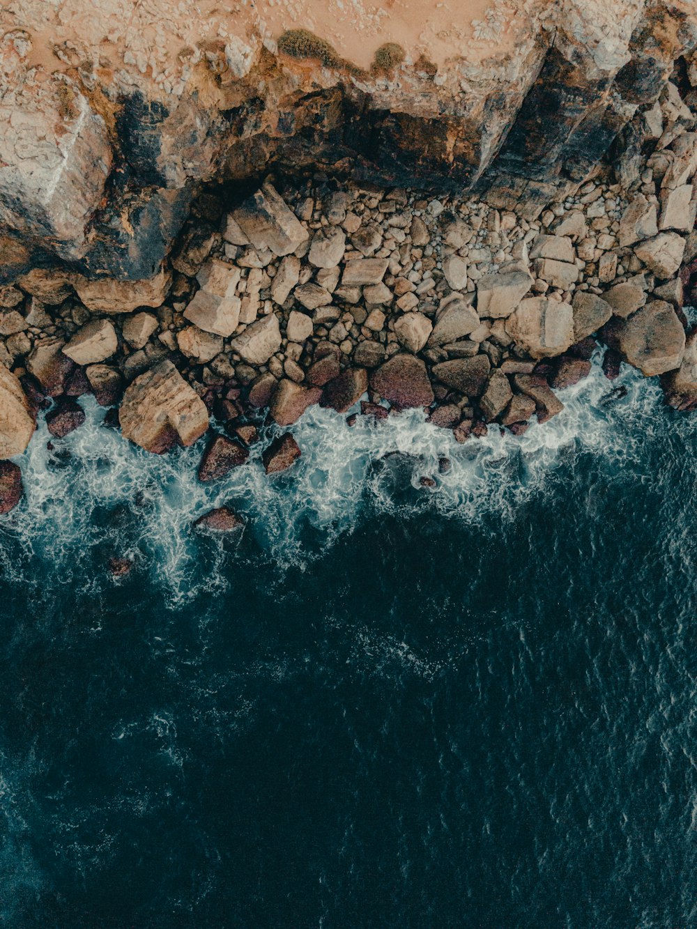 an aerial view of a rocky beach and ocean