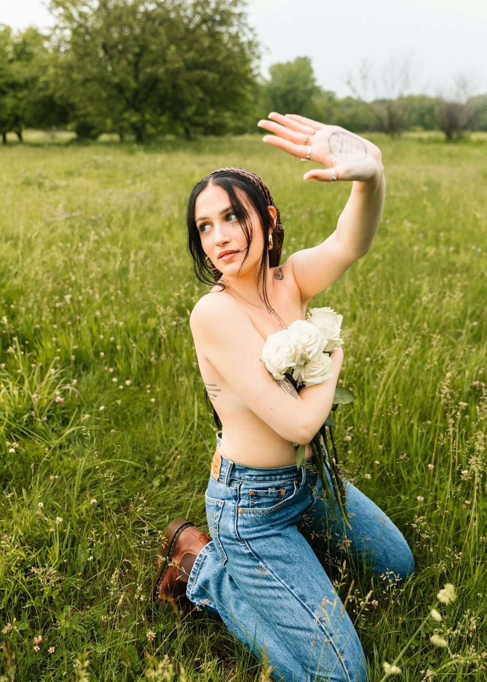 a woman sitting in a field holding a bouquet of flowers