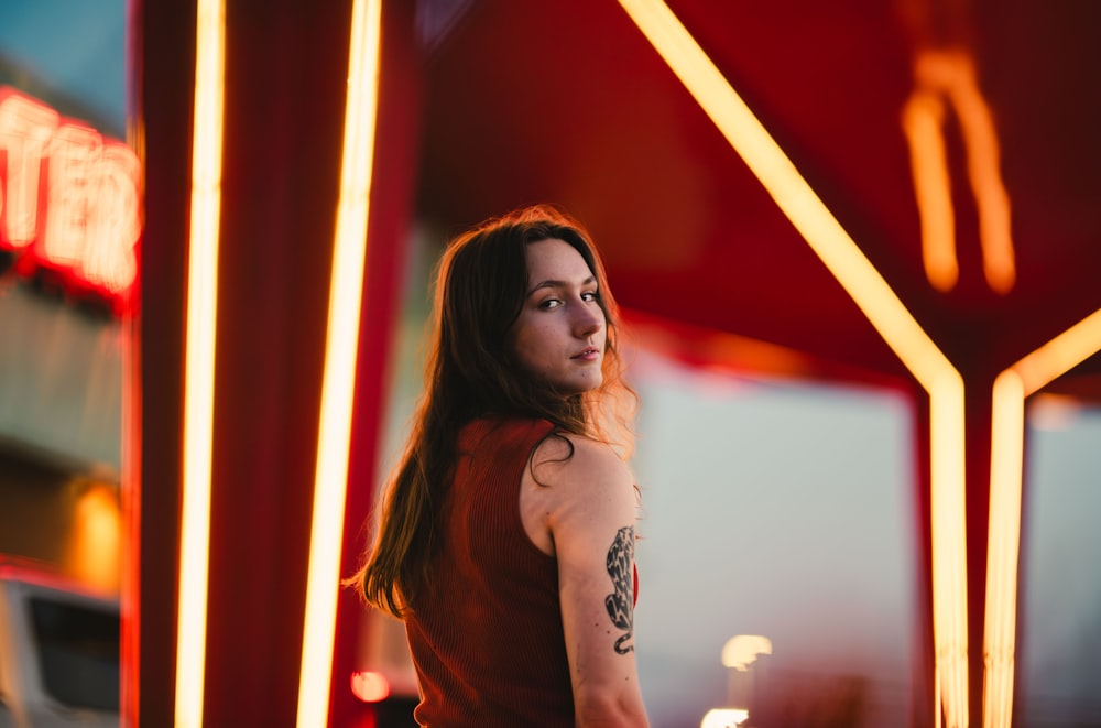 a woman standing in front of a neon sign