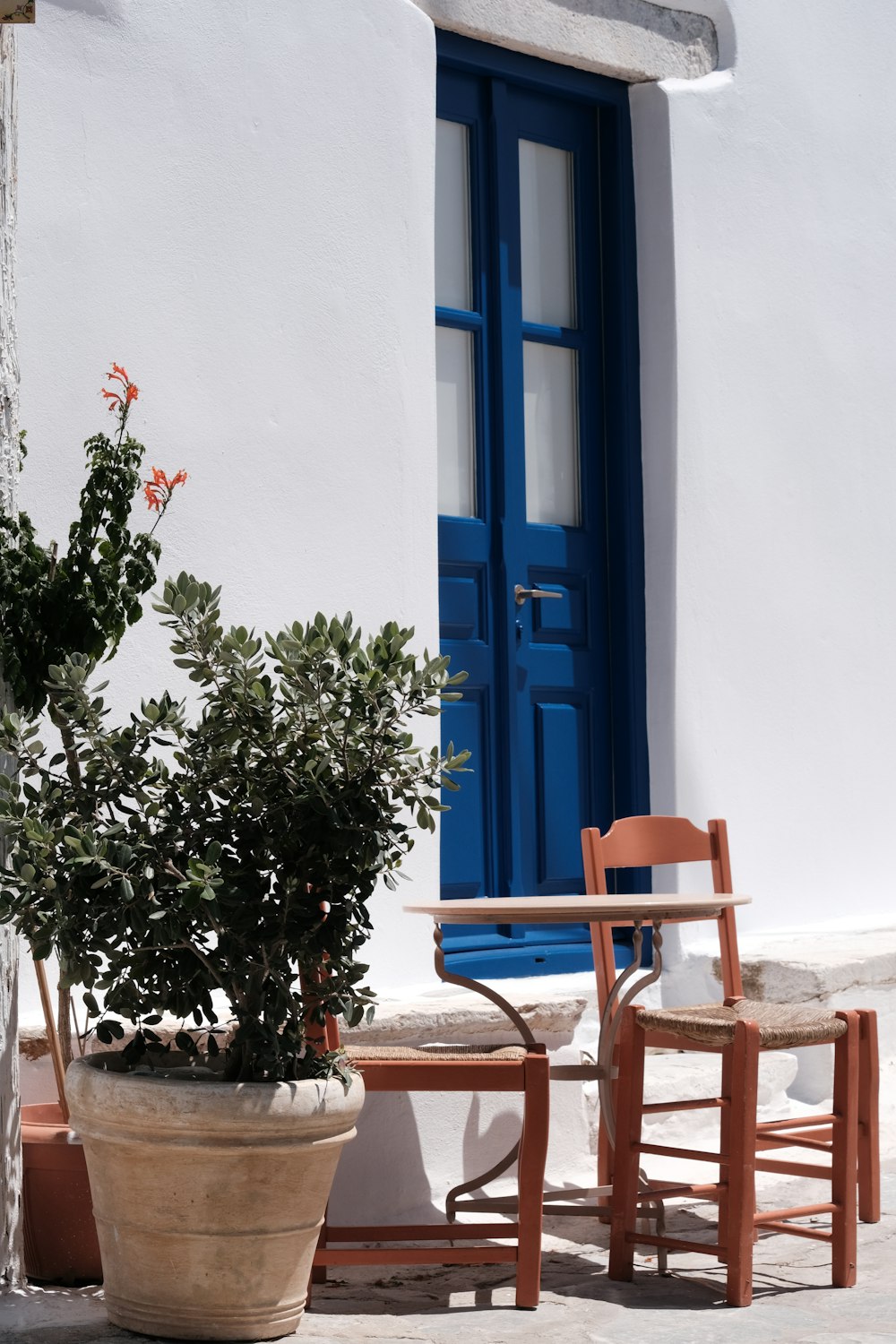 two chairs and a table in front of a blue door