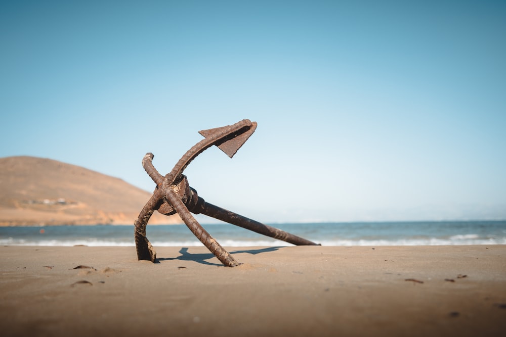 ein rostiger Anker an einem Strand mit einem Berg im Hintergrund