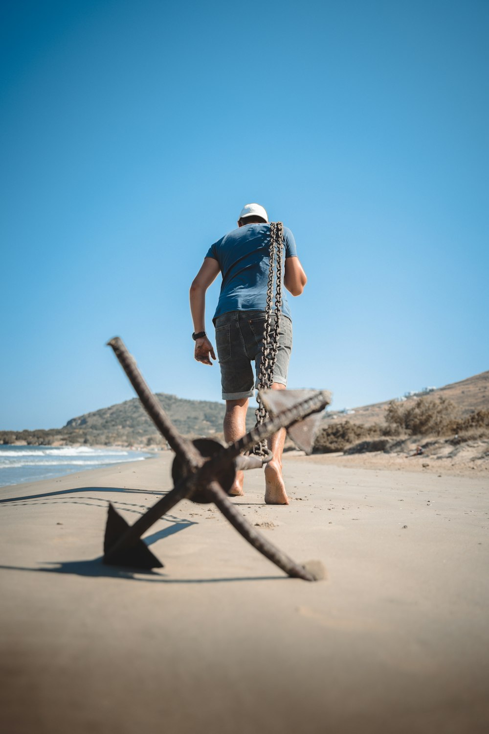 Ein Mann, der an einem Strand neben einem Anker spazieren geht