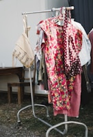 Casual summer dresses hanging on a clothes rack outdoors with greenery in the background.