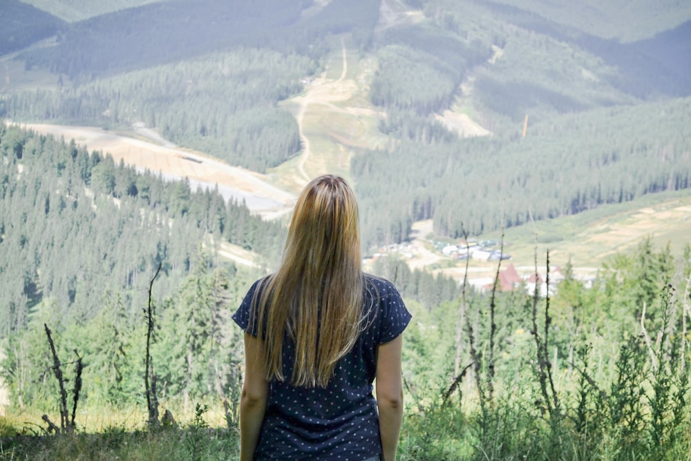 a woman standing on top of a lush green hillside