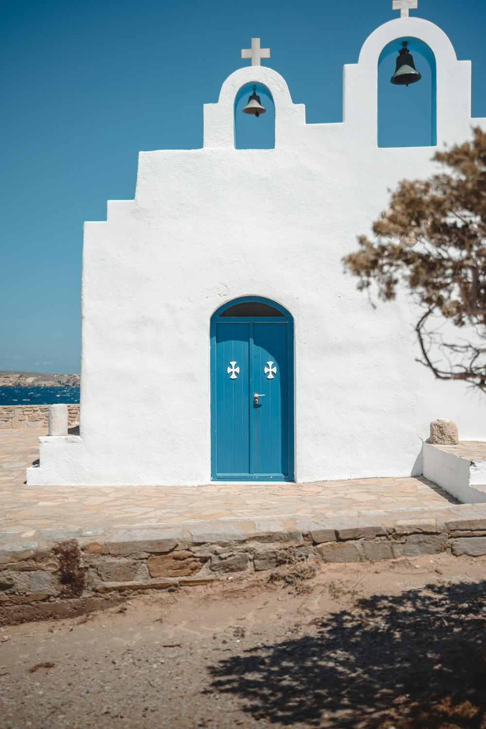 a white church with a blue door and two bells