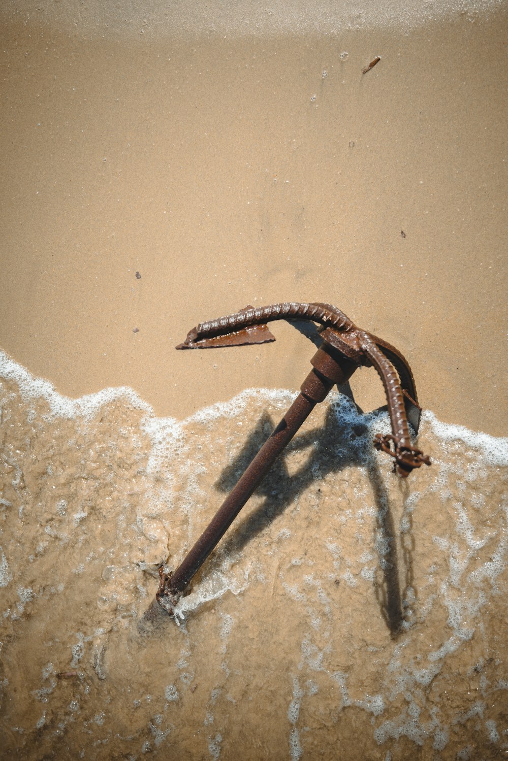 a rusty anchor laying on the sand of a beach