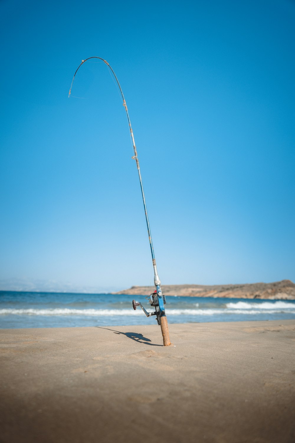 a fishing rod on the beach with a blue sky in the background