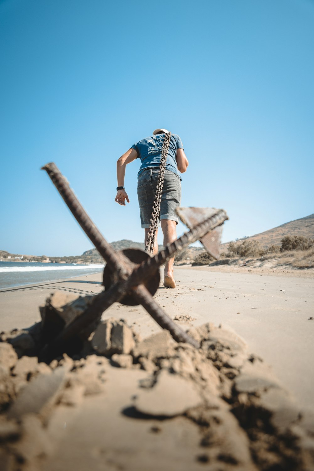 a man walking on a beach next to a large metal object