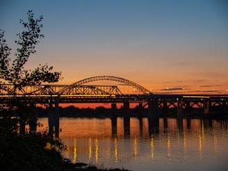 Sunset view of a completed bridge with smooth arches spanning a river.