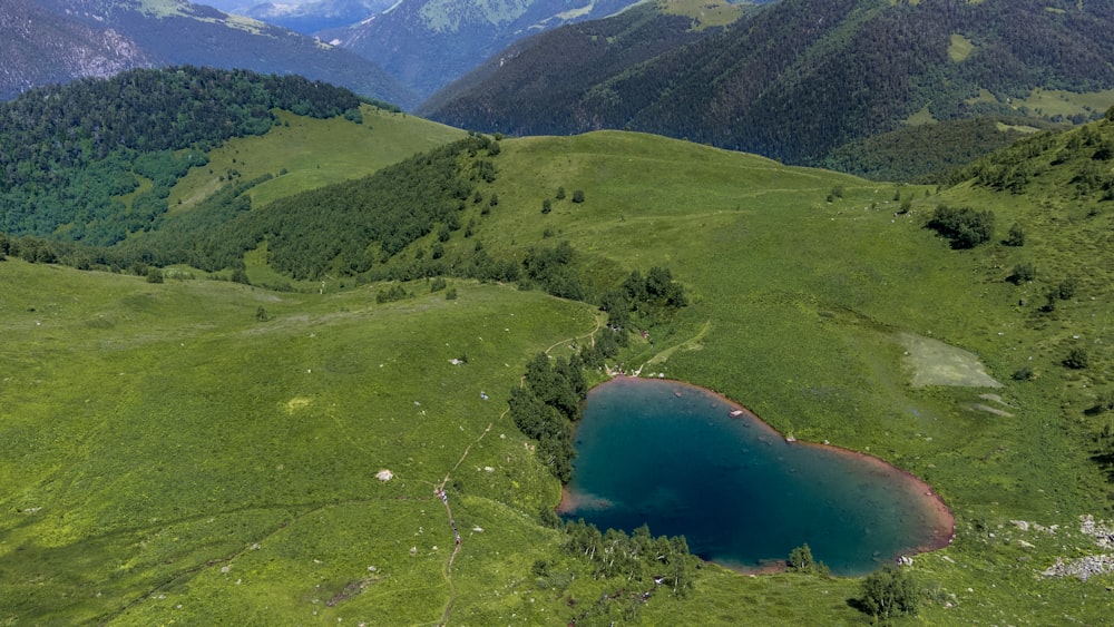 an aerial view of a green valley with a lake in the middle