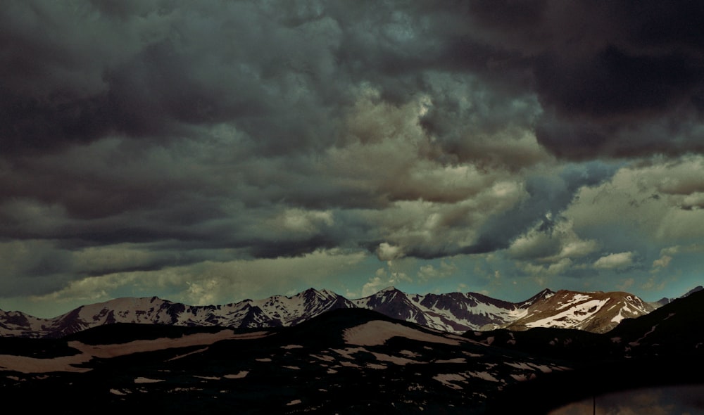 a mountain range under a cloudy sky with mountains in the background