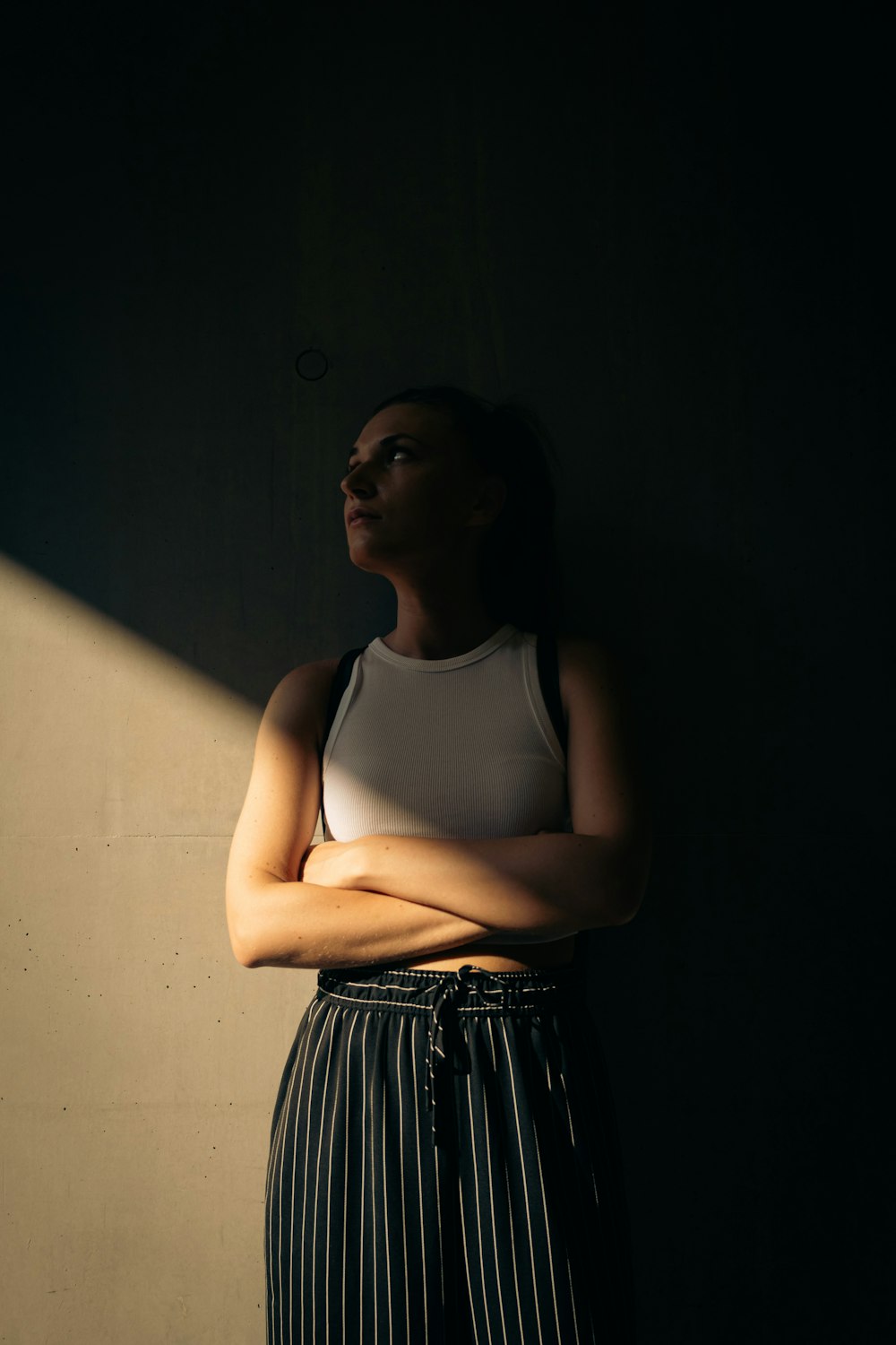 a woman standing in a dark room with her arms crossed