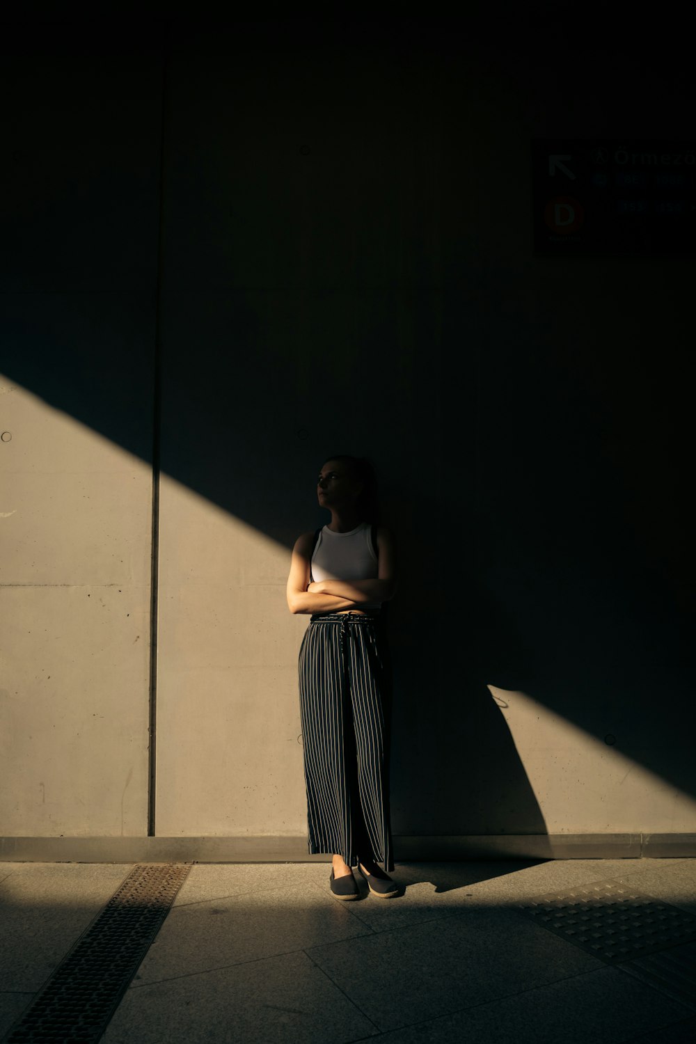 a woman leaning against a wall with her arms crossed