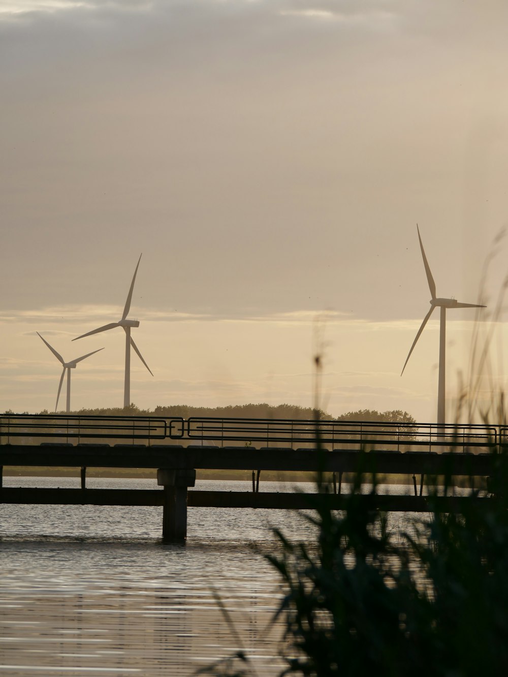 Un par de molinos de viento sentados en la parte superior de un puente