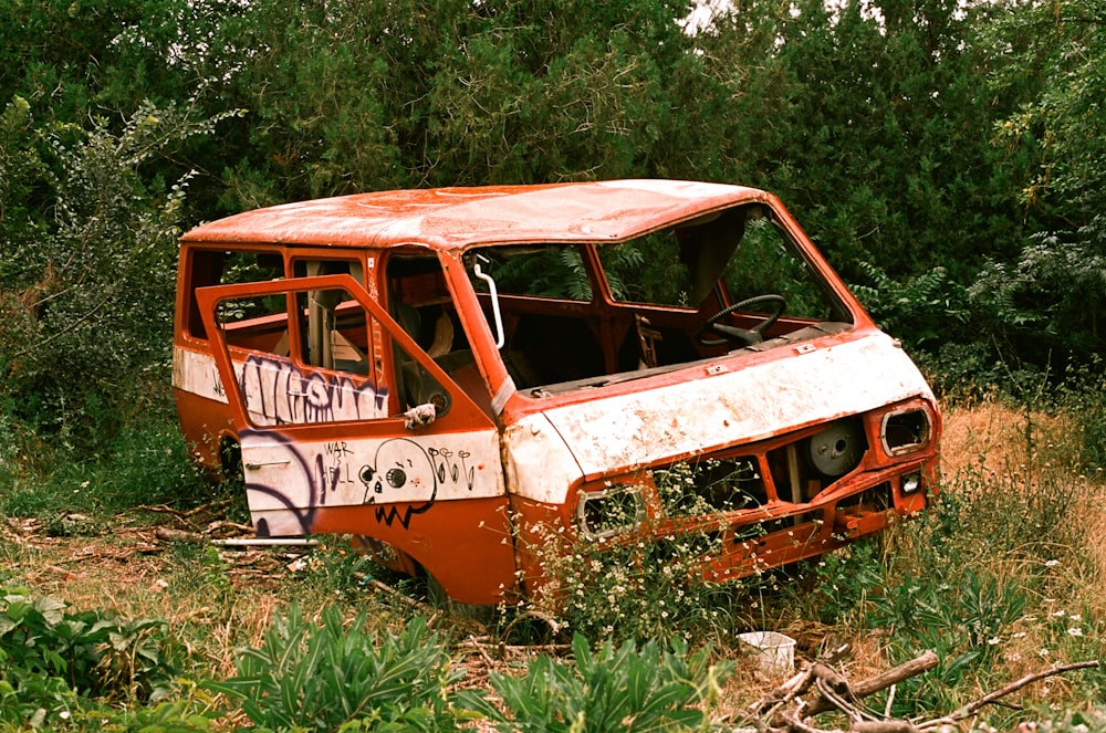 an old rusted out van sitting in a field