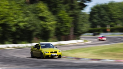 Close-up of a racing car speeding on a curvy circuit under golden sunlight.