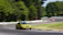 A thrilling shot of a race car speeding through a sharp corner on a sunny day.