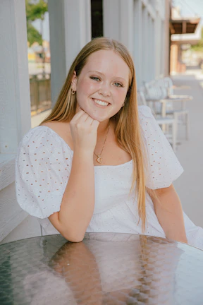 Casual outdoor scene with a young woman smiling, wearing layered necklaces and delicate rings in stainless steel.