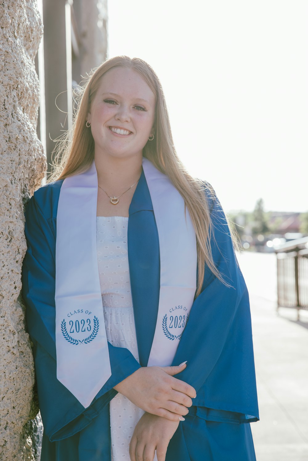 a woman in a graduation gown leaning against a tree