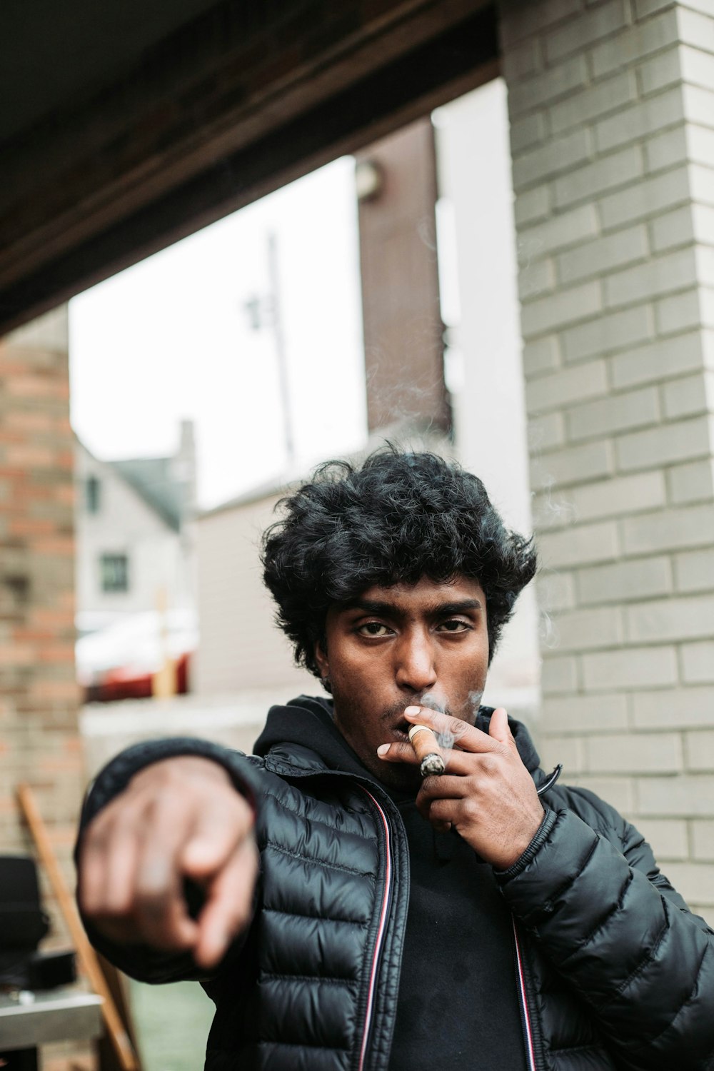 a man in a black jacket smoking a cigarette