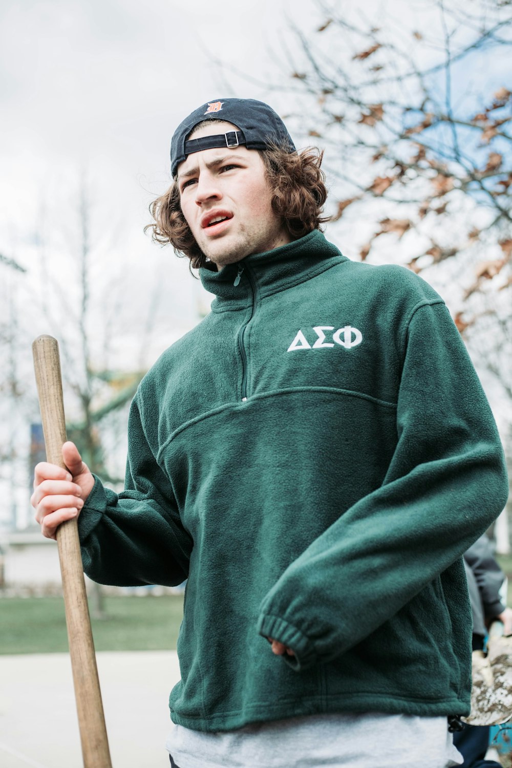 a man in a green jacket holding a baseball bat