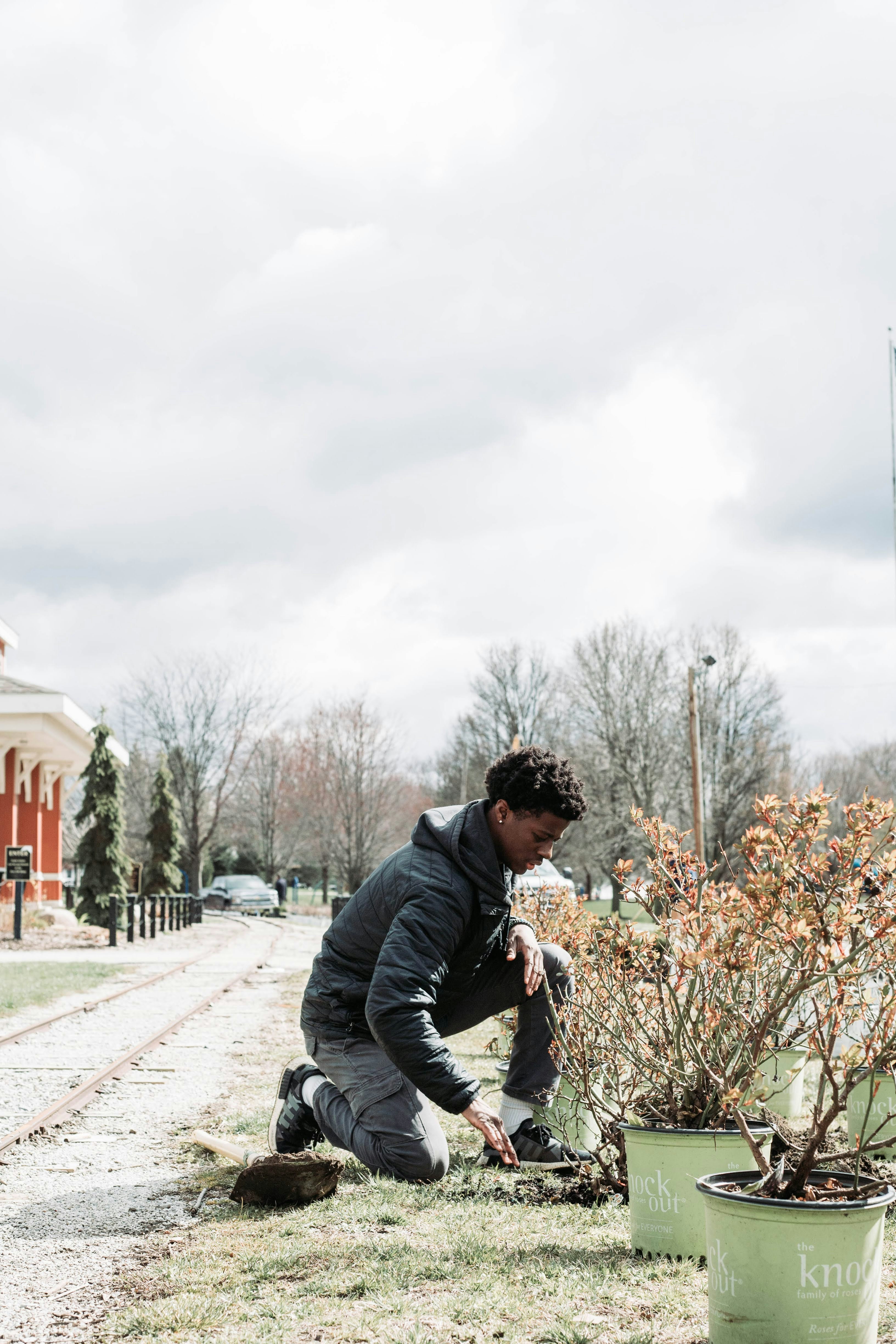 a man kneeling down next to a bush