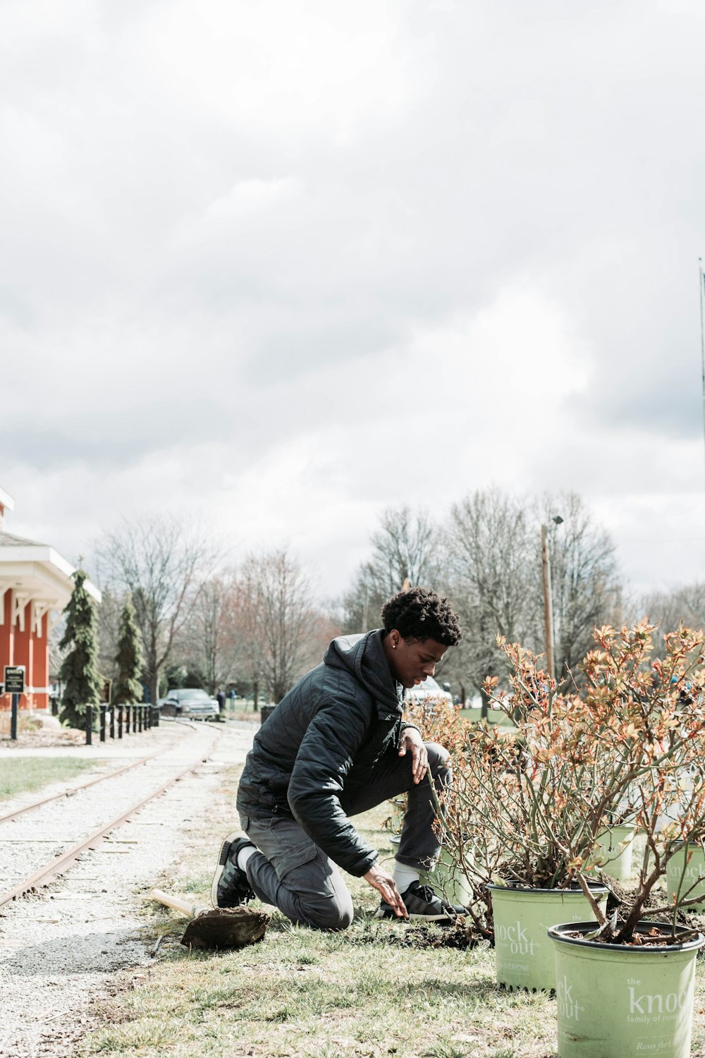 a man kneeling down next to a bush