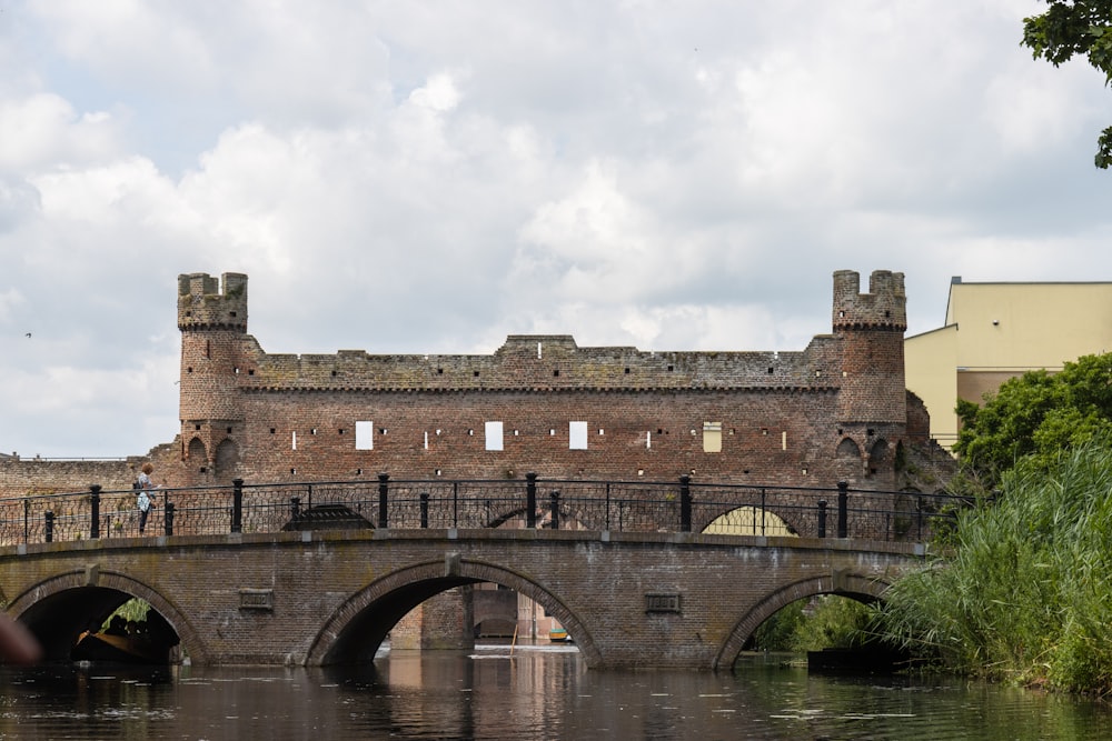 uma ponte sobre um corpo de água com um castelo ao fundo