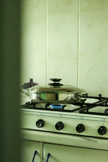 Technician carefully repairing a gas range cooker in a bright kitchen