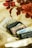 A collection of vintage cassette tapes is arranged on a cream-colored fabric with a floral pattern. The tapes are a mix of transparent, black, and white casings, and some have visible labels with text. The floral design features red and brown flowers.