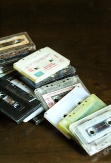 An overhead shot of well-worn cassette tapes spilling out of a bright yellow plastic case on a checkerboard table.