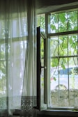 A soft linen curtain gently blowing by an open window overlooking a quiet street.