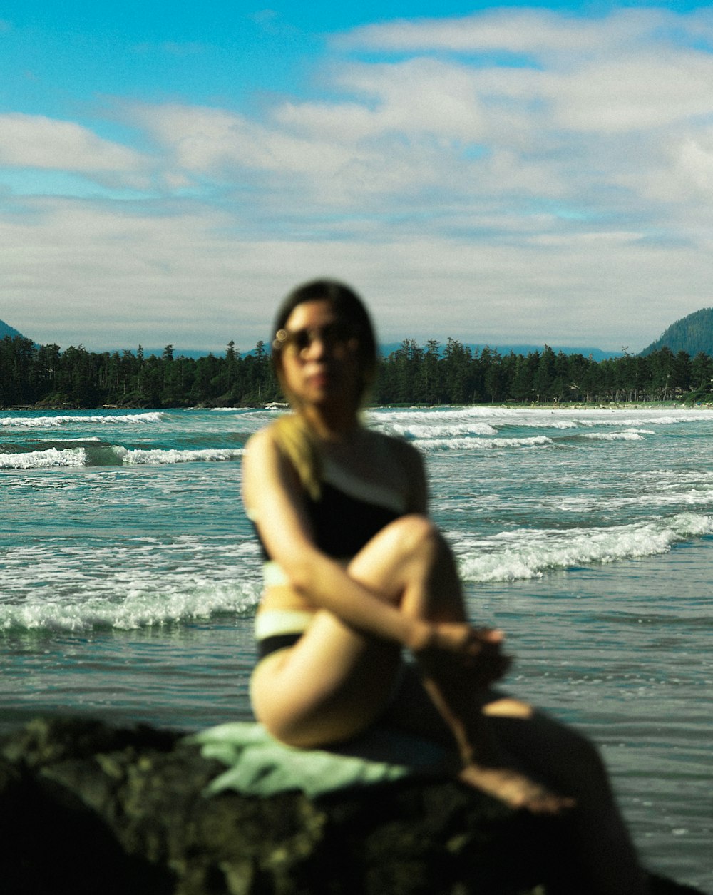 Una donna seduta su una roccia di fronte all'oceano