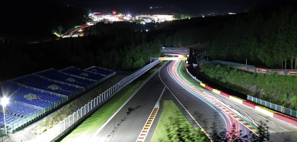 A sleek futuristic racing game track glowing under neon lights at night