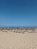 Wide shot of the beach with loungers and umbrellas facing the calm Mediterranean waters