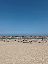 Wide shot of the beach with loungers and umbrellas facing the calm Mediterranean waters