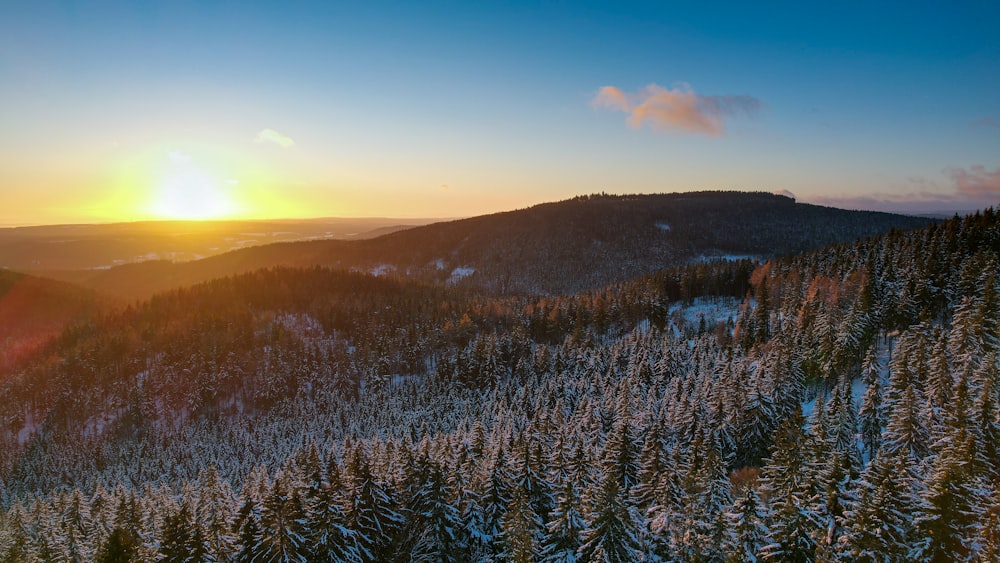 the sun is setting over a snowy mountain