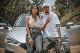 A happy couple standing beside their car, feeling secure and confident.
