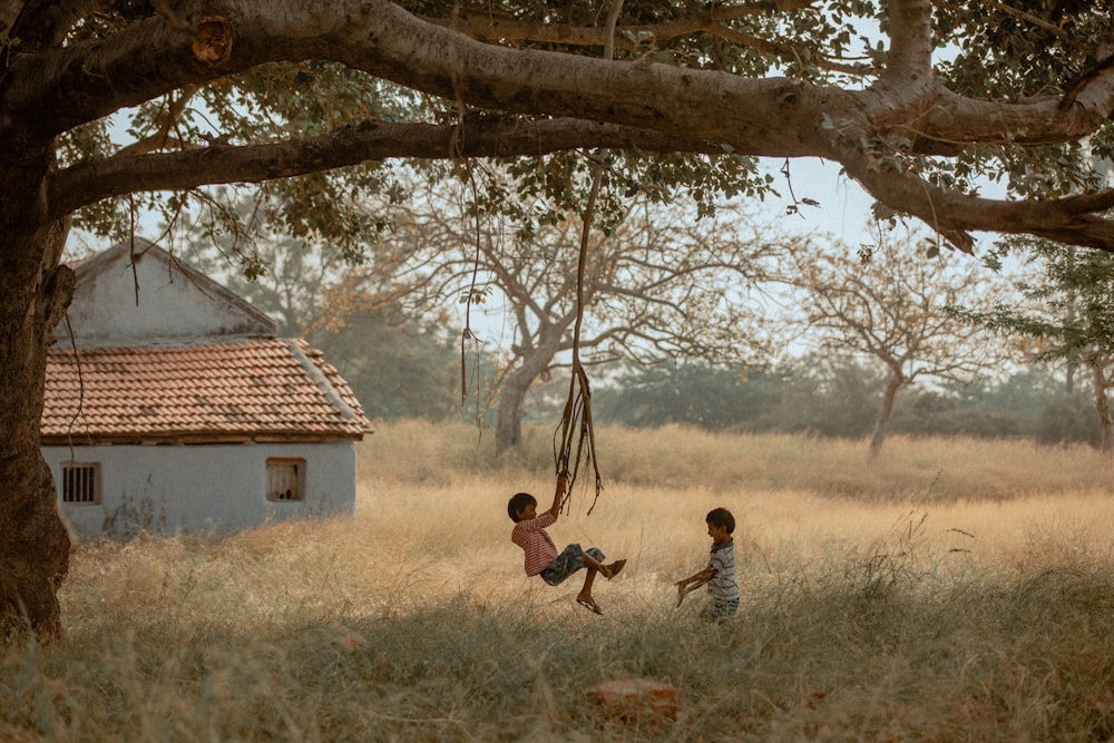 two children playing in a field with a house in the background