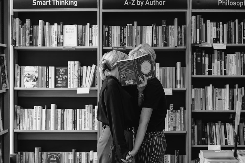 a couple of people standing in front of a book shelf