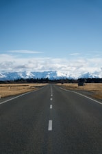 a long empty road with mountains in the background