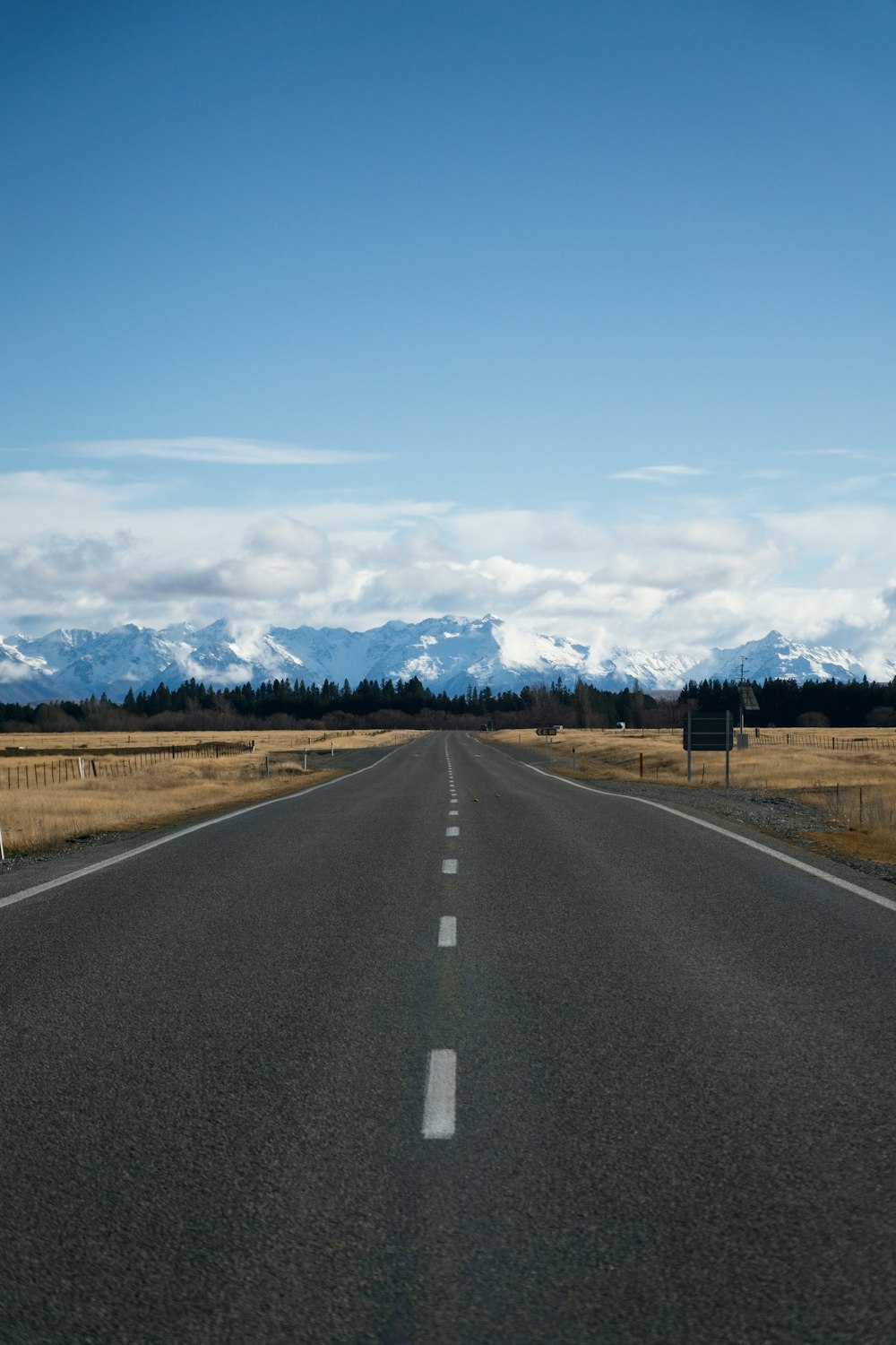 a long empty road with mountains in the background